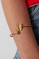 Bracciale rigido farfalla dorato **ispirato alla natura** indossato su un polso, mostrando il design elegante e minimalista per il look quotidiano.