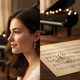 Modella in primo piano che indossa orecchini a pendente in argento 925 a chiave di sol con zircone. La sezione di destra mostra un paio degli stessi orecchini in primo piano su spartito. Gioielli per donna e bambina a tema musica