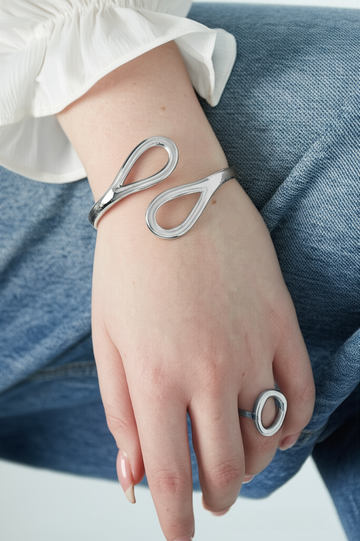 Bracciale rigido argento a goccia **minimal**in acciaio inossidabile, indossato al polso  in abbinamento con finitura lucida.